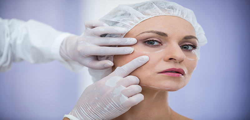 Doctor examining female patients face for dermatology treatment